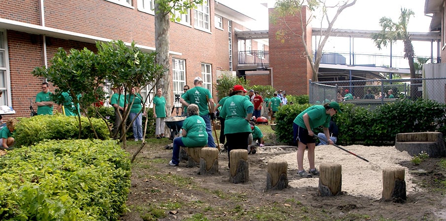 Playground builder volunteers spread mulch at a community park.
