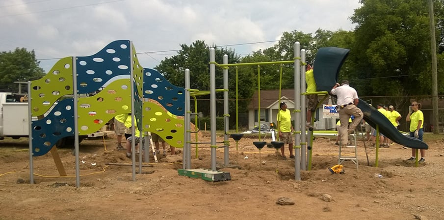 Community volunteers constructing a PlayBooster playground with slide and 4-panel Cascade Climber. 
