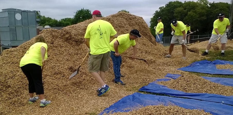 Volunteers adding wood chips to playground surfacing area