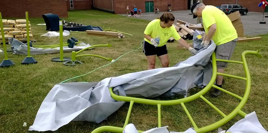 Volunteers unpacking and laying out playground equipment for a Playground Build.
