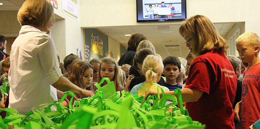A class of children stand waiting to receive their Green Apple Day of Service gift bag.