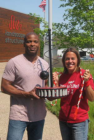Landscape Structures employees standing outside the office building holding a trophy.
