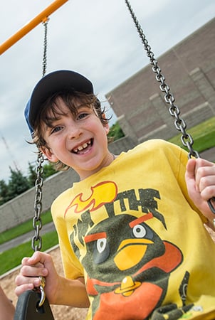 Young boy swinging at a playground.