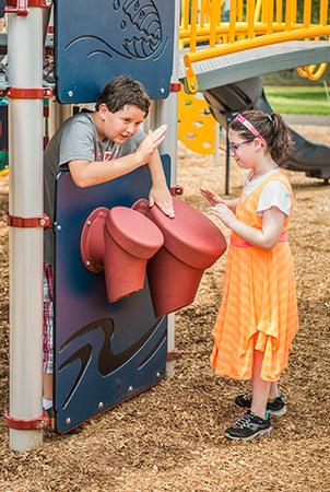 Two kids playing on a PlayBooster playground drum Bongo Panel.