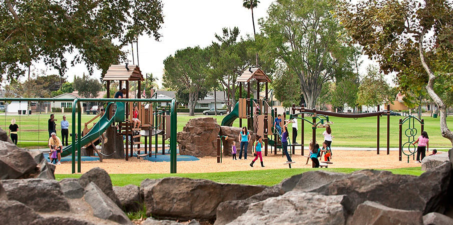 Cabin-themed playground with Pinnacle rock climber at a community park.
