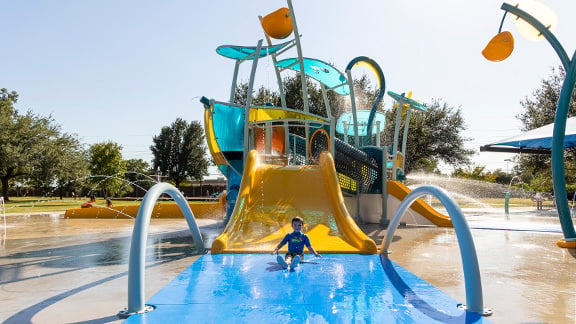 A boy going down a slide at a splash park