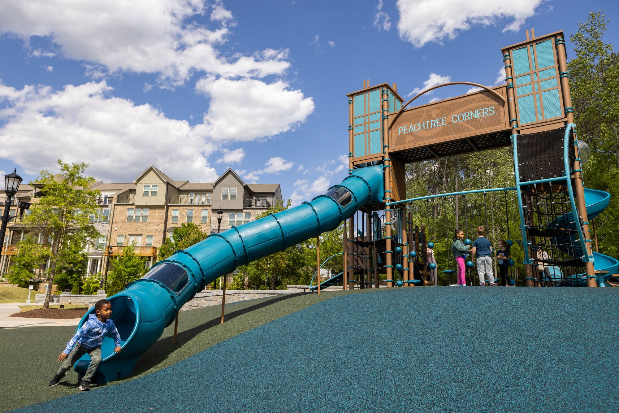 A boy emerges from a long tunnel slide, which is a popular slide for playgrounds, at the Peachtree Town Green playground