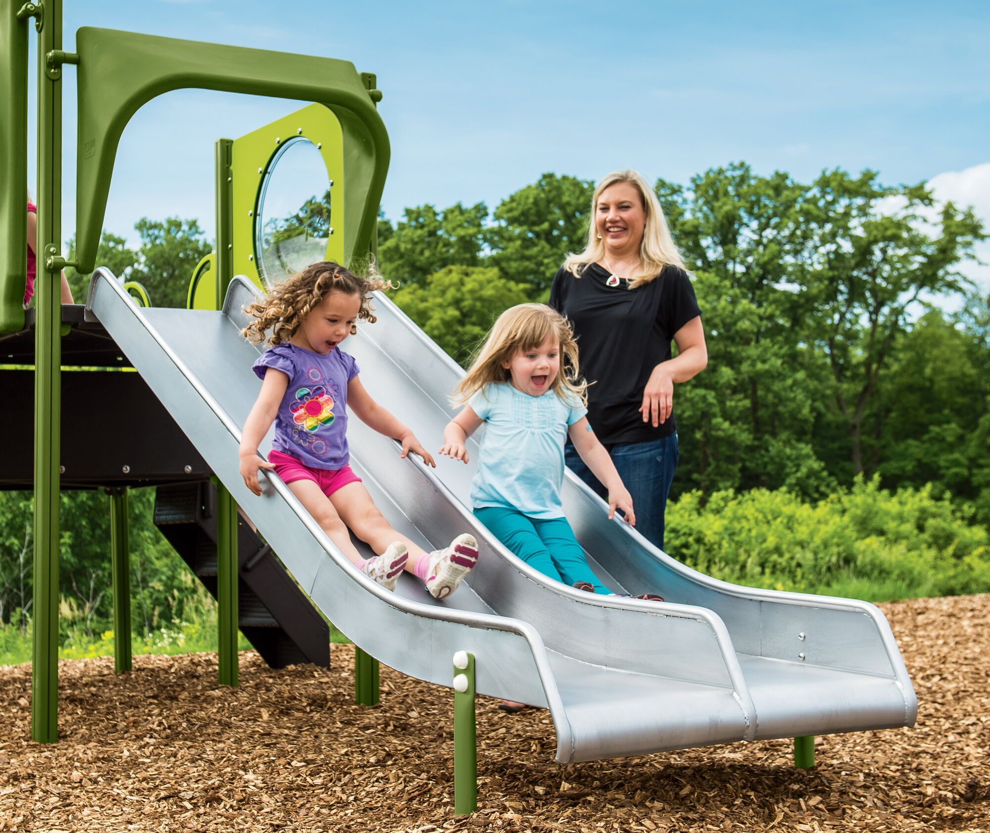 Two girls slide down a stainless steel double playground equipment slide