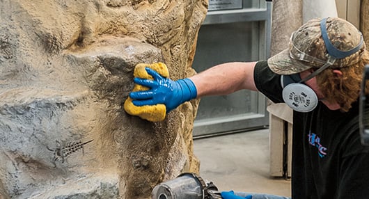 Man painting concrete rock formation