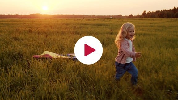 Video still of little girl pulling a kite along the ground at sunset.