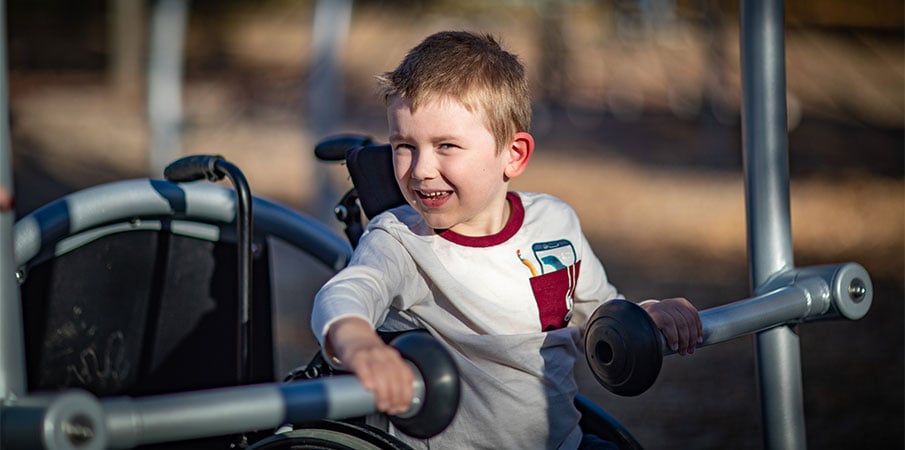 Close up on little boy in wheelchair riding in We-Go-Swing.