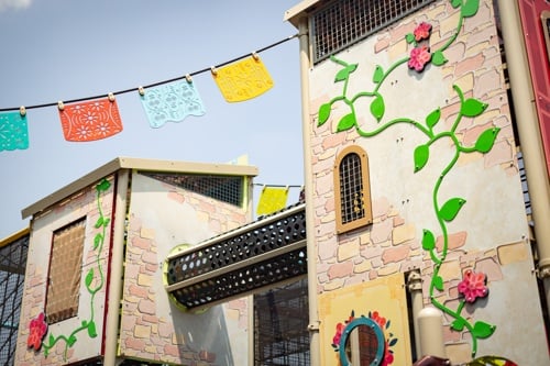 Green vine created with metal panels curve up the side of a custom playground structure