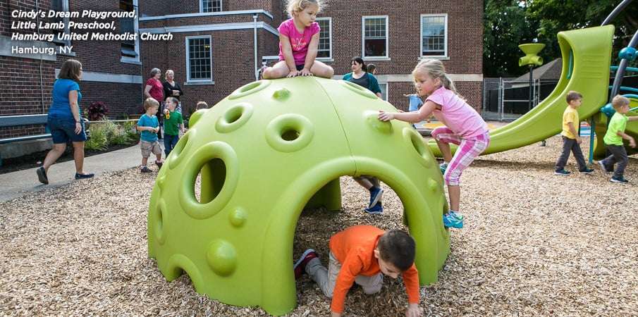 Lime green Cozy Dome in the foreground at Hamburg United Methodist Church, with children playing.