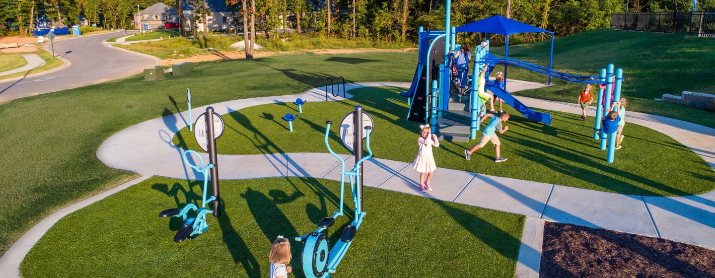 A young girl uses outdoor exercise equipment to exercise in a park