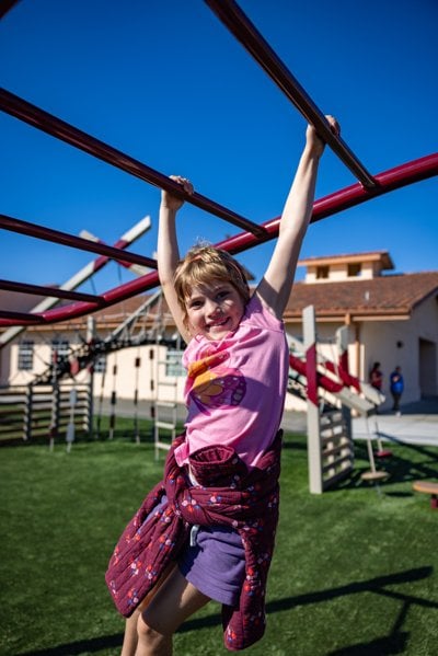 Girl hangs from overhead bars on a playground