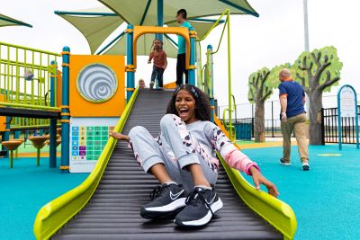 Girl laughs while sliding down a roller slide