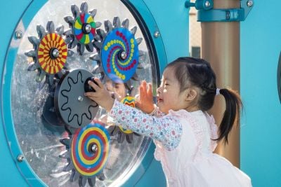 Girl on playground reaches for gear panel