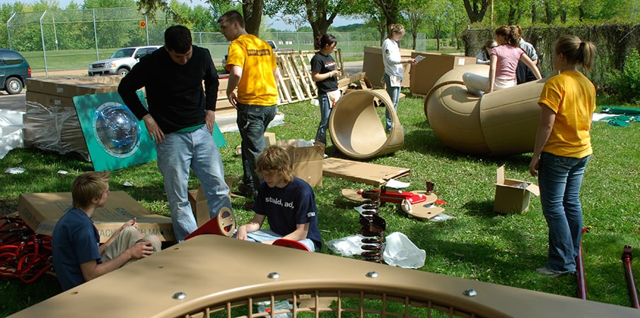Volunteers assembling playground equipment in the grass.