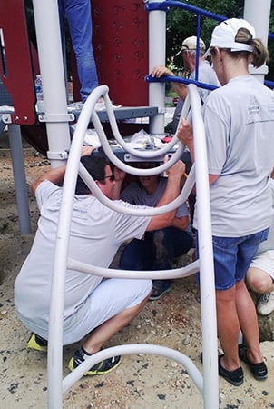 Volunteers installing Loop Arch Climber on a new playground.