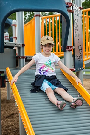 Young girl sliding down a sensory playground Roller slide.