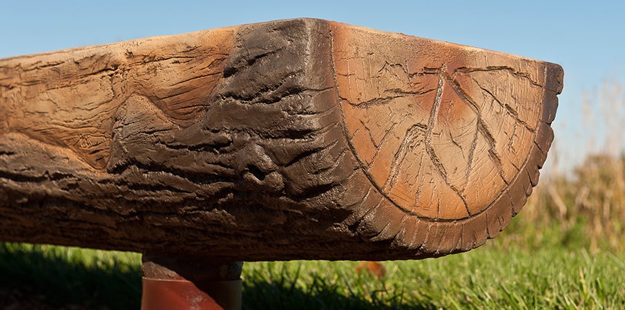 The end of a realistic designed and carved concrete log bench.