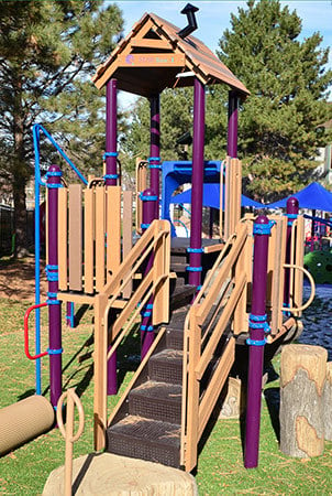 A natural wood color and purple and blue PlayBooster play structure. 