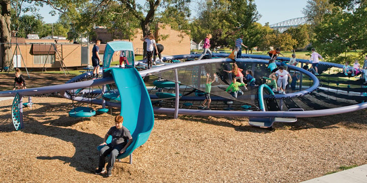 Children play on a huge figure-eight shaped Quantis netplay structure that has a turquoise blue slide. 