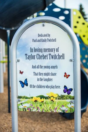 A sign reading "Dedicated by Paul and Emily Twitchell in Loving Memory of Taylor Chebet Twitchell" 
