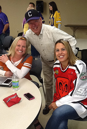 Landscape Structures founder Steve King smiles for the camera with two employees as they wear sports attire on Team Spirit Day.